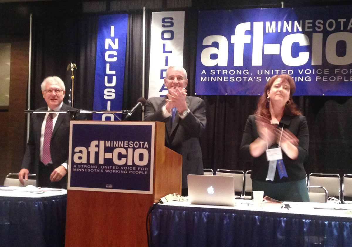 Governor Mark Dayton acknowledged the applause of union members at the Minnesota AFL-CIO convention. With him are federation President Bill McCarthy and Secretary-Treasurer Julie Blaha. Workday Minnesota photo