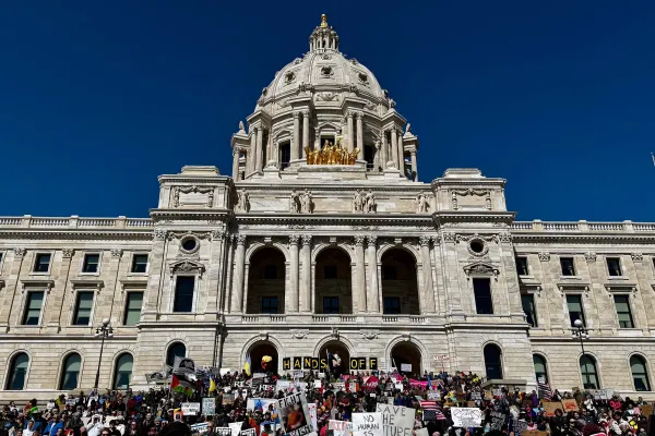 Minnesota State Capitol with a large group of people in front of it. The sky is deep blue behind the Capitol Dome.