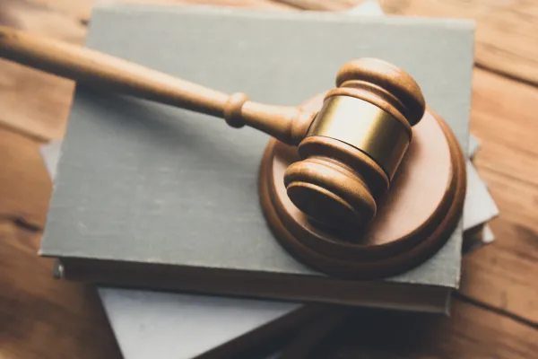 Photo of a gavel on a stack of books on a wooden desk.
