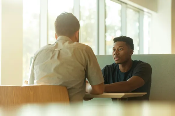 Photo of two people sitting at a table having a conversation.