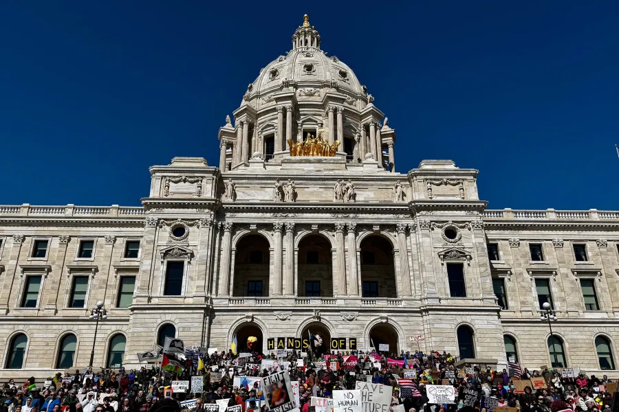 Minnesota State Capitol with a large group of people in front of it. The sky is deep blue behind the Capitol Dome.