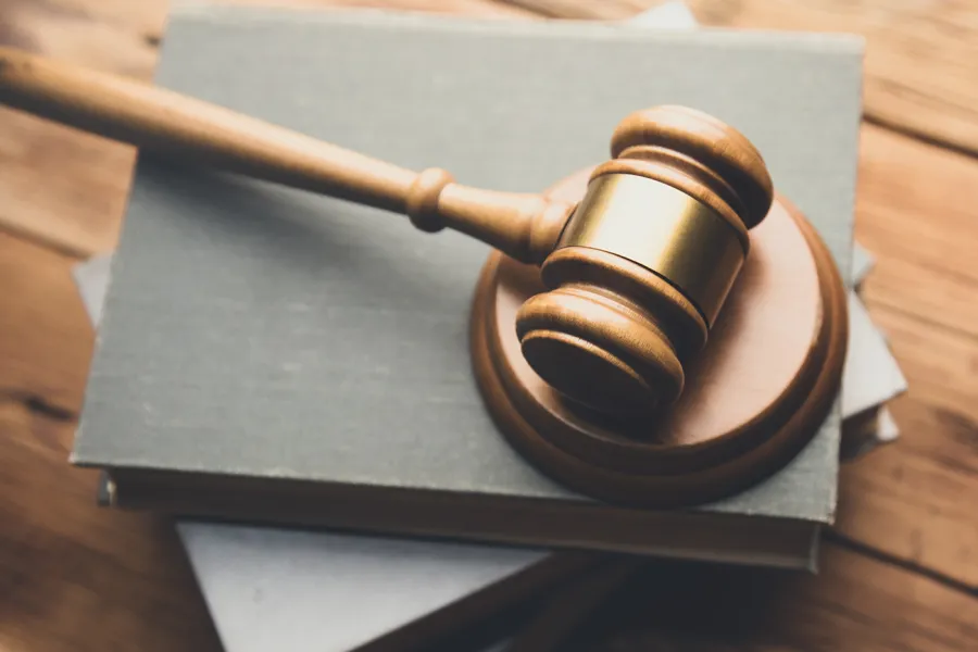 Photo of a gavel on a stack of books on a wooden desk.