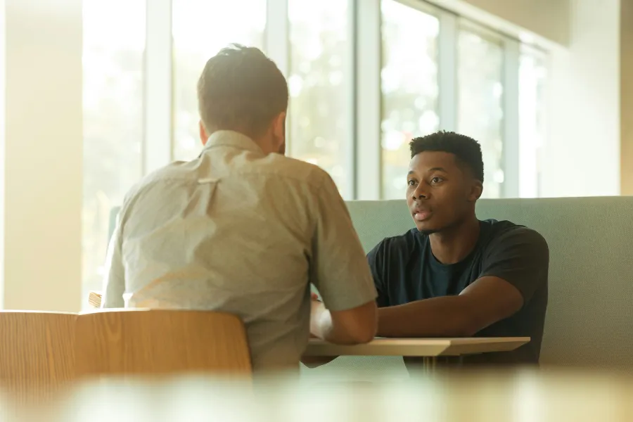 Photo of two people sitting at a table having a conversation.